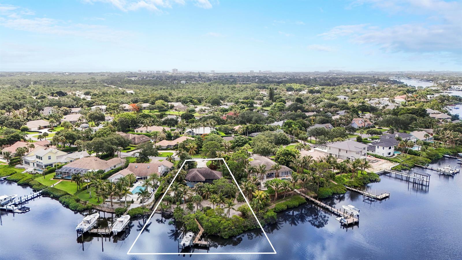 An aerial view shows a waterfront house with a private dock and surrounding tropical vegetation — 18791 SE River Ridge Road, Jupiter FL 33469, JUPITER, FL
