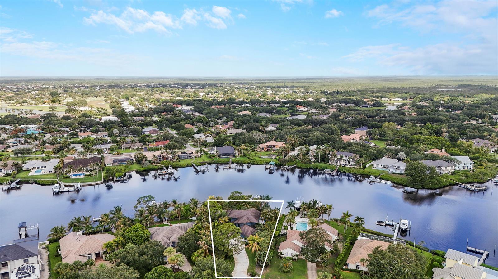 An aerial view shows a waterfront house with a long driveway and surrounding tropical landscaping — 18791 SE River Ridge Road, Jupiter FL 33469, JUPITER, FL