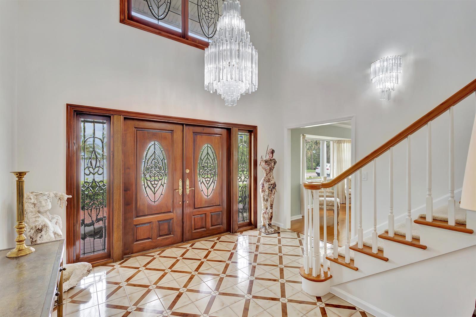 A grand foyer features a crystal chandelier, double wooden doors, and a patterned tile floor — 1141 Pine Point Road, West Palm Beach FL 33404, WEST PALM BEACH, FL