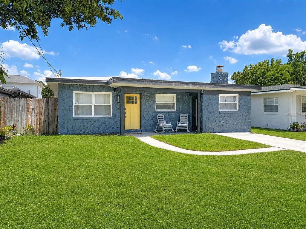 A single-story house with a blue stone facade, a yellow front door, and a lawn — 3313 W KATHLEEN STREET, TAMPA, FL
