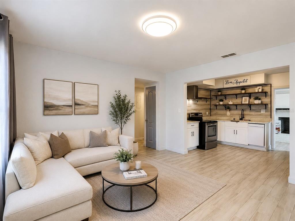 A living room with a sectional sofa and coffee table opens into a modern kitchen — 3313 W KATHLEEN STREET, TAMPA, FL