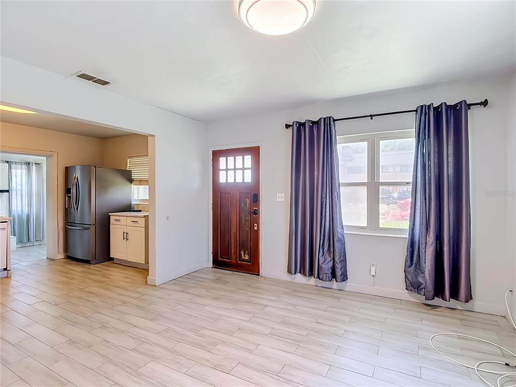 A kitchen features white cabinets, stainless steel appliances, open shelving, and light wood-look tile flooring — 3313 W KATHLEEN STREET, TAMPA, FL
