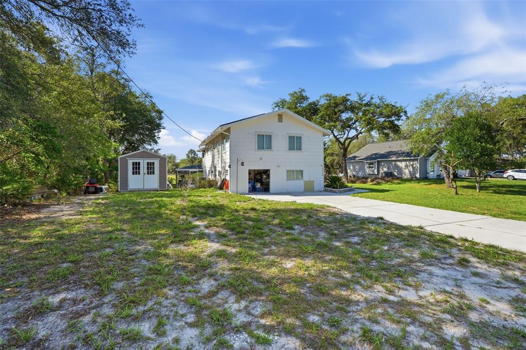 A two-story white house with a garage and a detached shed sits on a lot — 10226 LYNNHAVEN ROAD, SPRING HILL, FL
