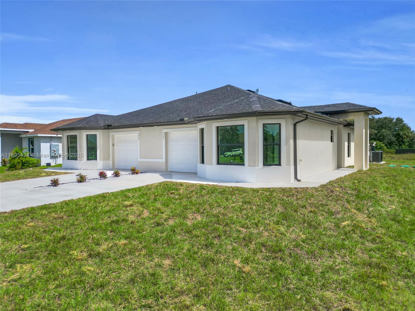 A modern, single-story duplex with two white garage doors and a light-colored stucco exterior — 2508 Park Rd, Lehigh Acres FL 33971, LEHIGH ACRES, FL