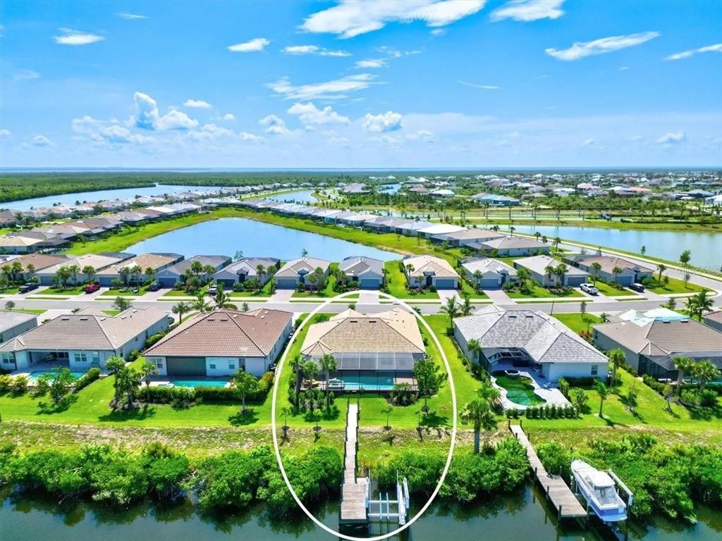 An aerial view shows a waterfront house with a pool, screened lanai, and private dock — 15024 SPANISH POINT DRIVE, PORT CHARLOTTE, FL