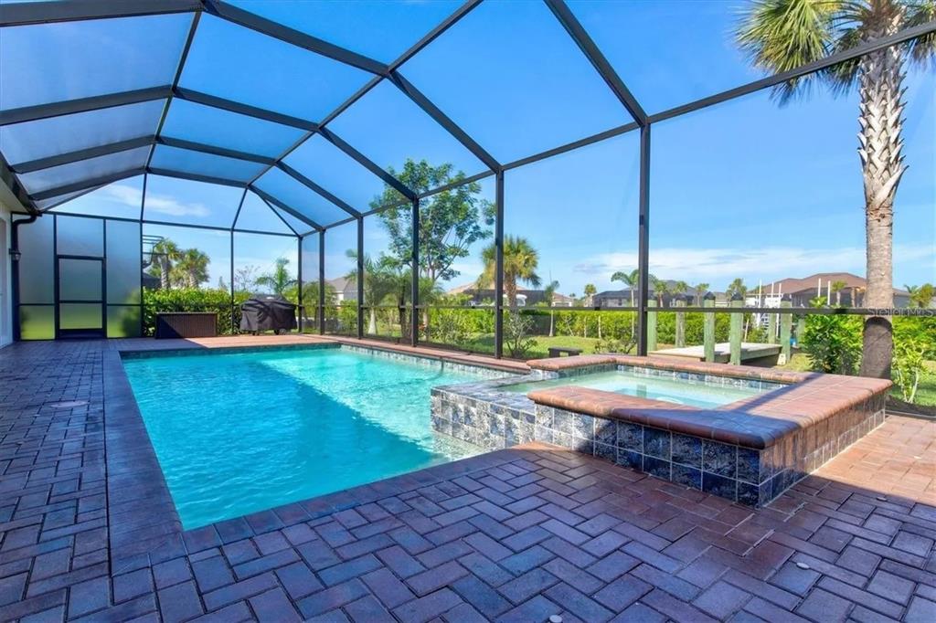 A screened-in pool and spa area with brick pavers and a view of the backyard — 15024 SPANISH POINT DRIVE, PORT CHARLOTTE, FL