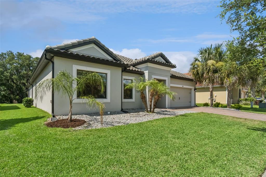 A single-story house with a gray stucco exterior, a tiled roof, and a paved driveway — 3874 BOWFIN TRAIL, KISSIMMEE, FL