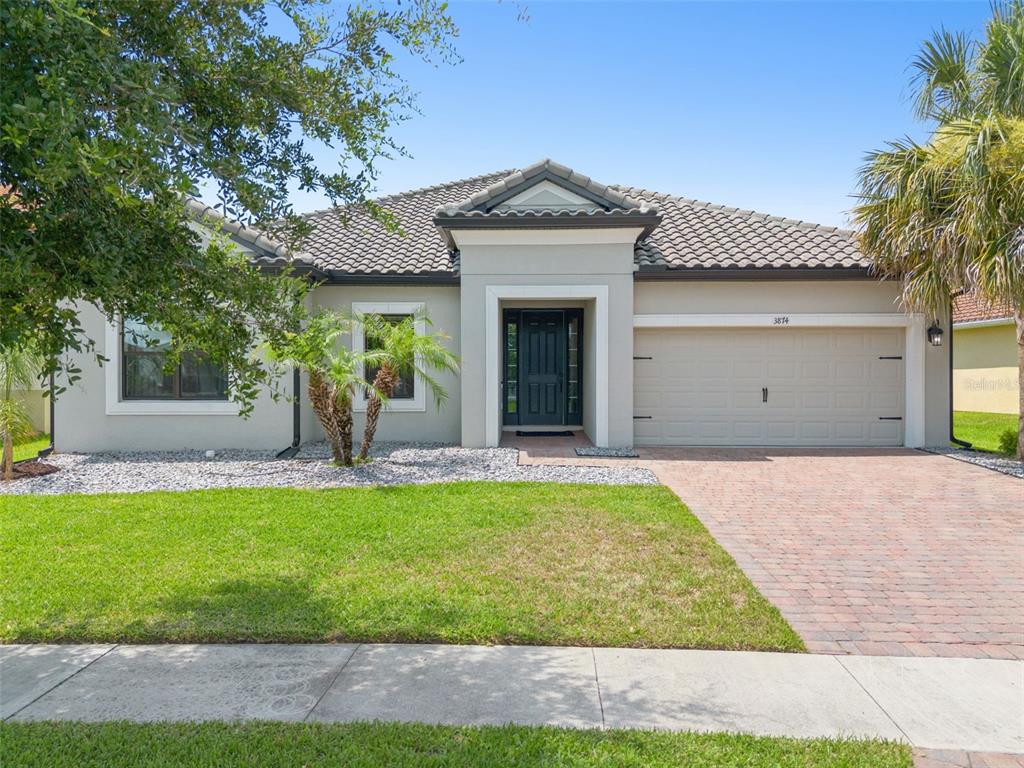 A single-story house with a beige stucco exterior, a tiled roof, and a paved driveway — 3874 BOWFIN TRAIL, KISSIMMEE, FL