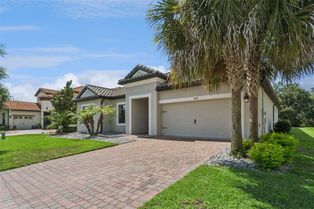 A single-story house with a paved driveway, a two-car garage, and a palm tree — 3874 BOWFIN TRAIL, KISSIMMEE, FL