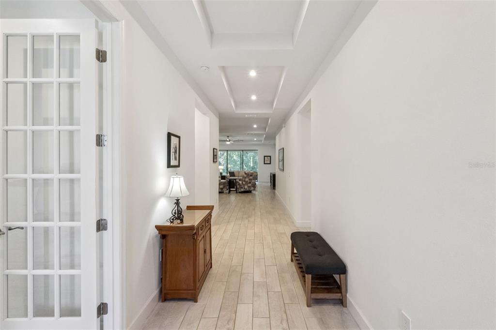 A bright hallway with white walls, tile flooring, and a tray ceiling leads to a living area — 3874 BOWFIN TRAIL, KISSIMMEE, FL