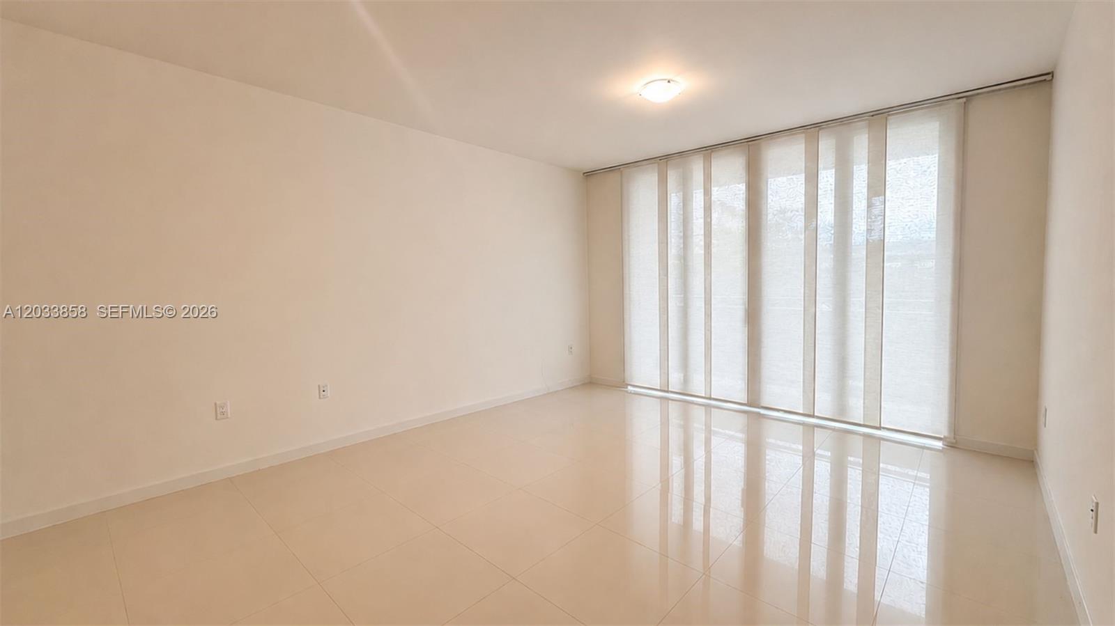 An empty room features light-colored tile flooring, white walls, and floor-to-ceiling sliding glass doors — 7825 NW 107th Ave # 218, Doral FL 33178, DORAL, FL