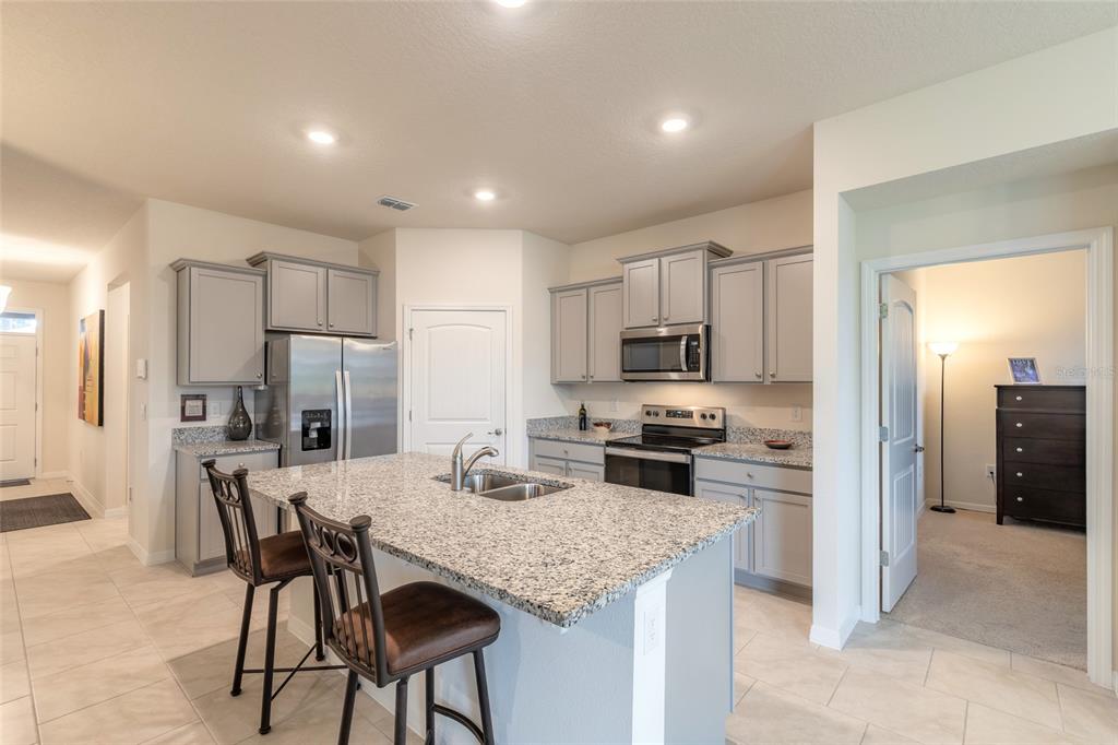 A kitchen with gray cabinets, granite countertops, a central island, and stainless steel appliances — 1413 SYLES DRIVE, NEW SMYRNA BEACH, FL