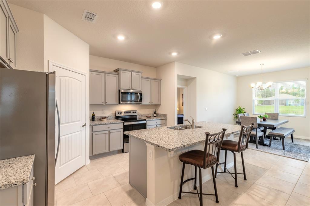 A kitchen with gray cabinets, granite countertops, a center island, and an adjacent dining area — 1413 SYLES DRIVE, NEW SMYRNA BEACH, FL