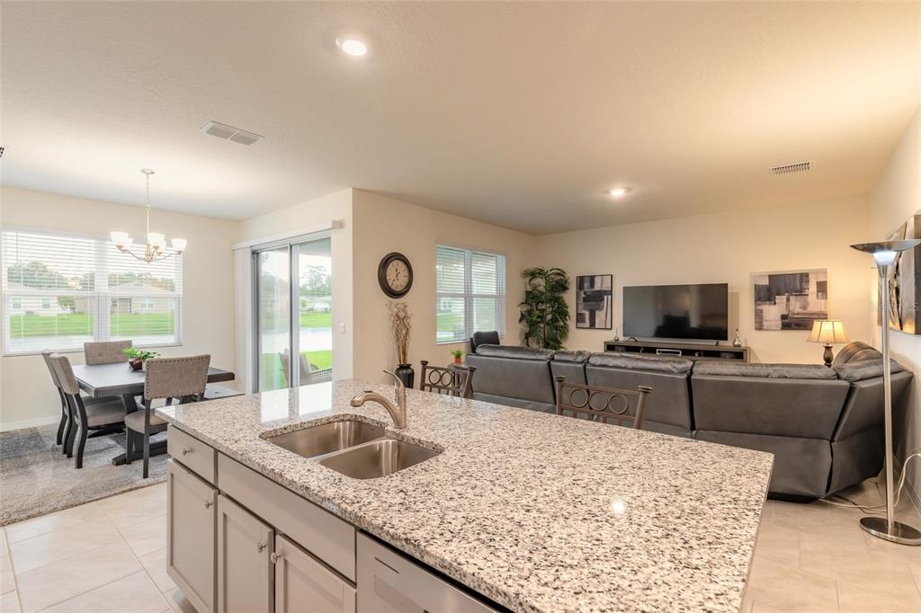 A kitchen island with granite countertops overlooks an open-concept living and dining area — 1413 SYLES DRIVE, NEW SMYRNA BEACH, FL