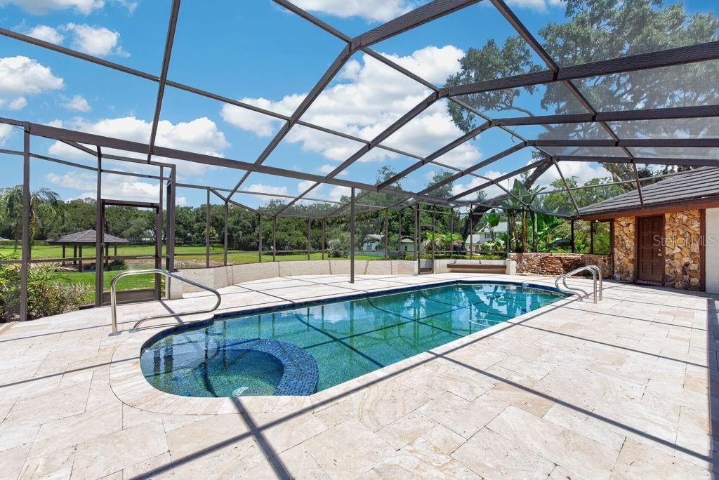A screened-in swimming pool and spa with stone decking and a view of the yard — 1007 LAKEWOOD DRIVE, BRANDON, FL