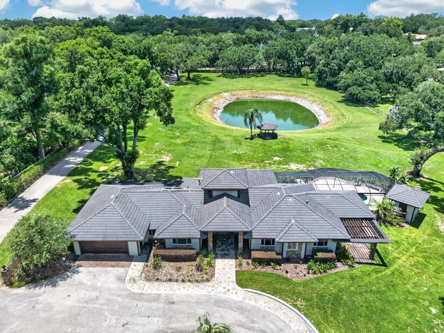 An aerial view of a house with a tiled roof, pool, and a pond — 1007 LAKEWOOD DRIVE, BRANDON, FL