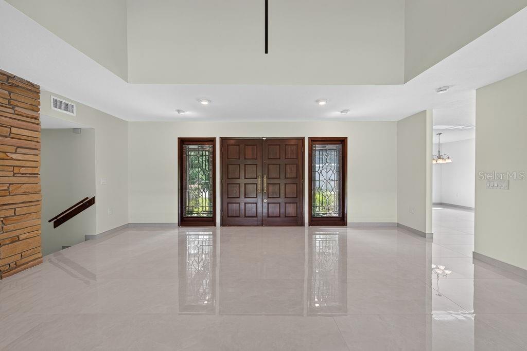 A spacious foyer features a double front door, tile flooring, and a high vaulted ceiling — 1007 LAKEWOOD DRIVE, BRANDON, FL
