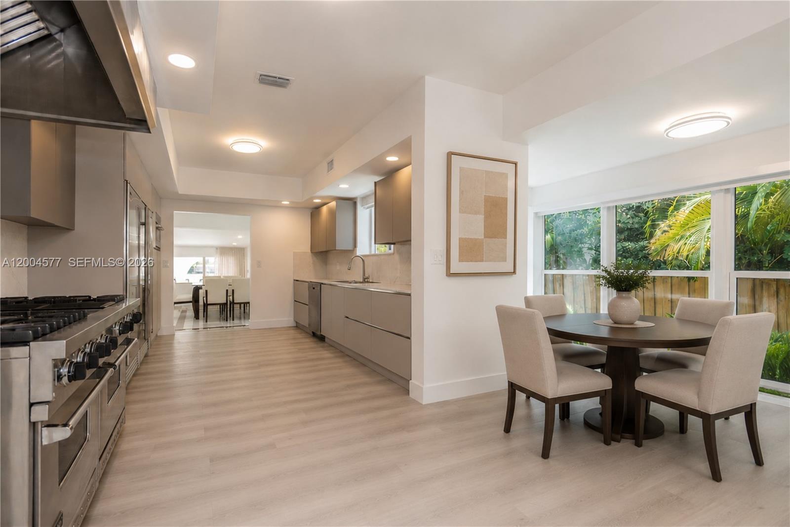 A modern kitchen with stainless steel appliances and a dining area with floor-to-ceiling windows — 1690 Daytonia Rd, Miami Beach FL 33141, MIAMI BEACH, FL