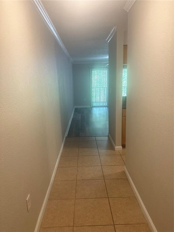A hallway with tan tile flooring leads toward a living area with wood-look flooring — 10100 SAILWINDS BOULEVARD N UNIT 206, LARGO, FL