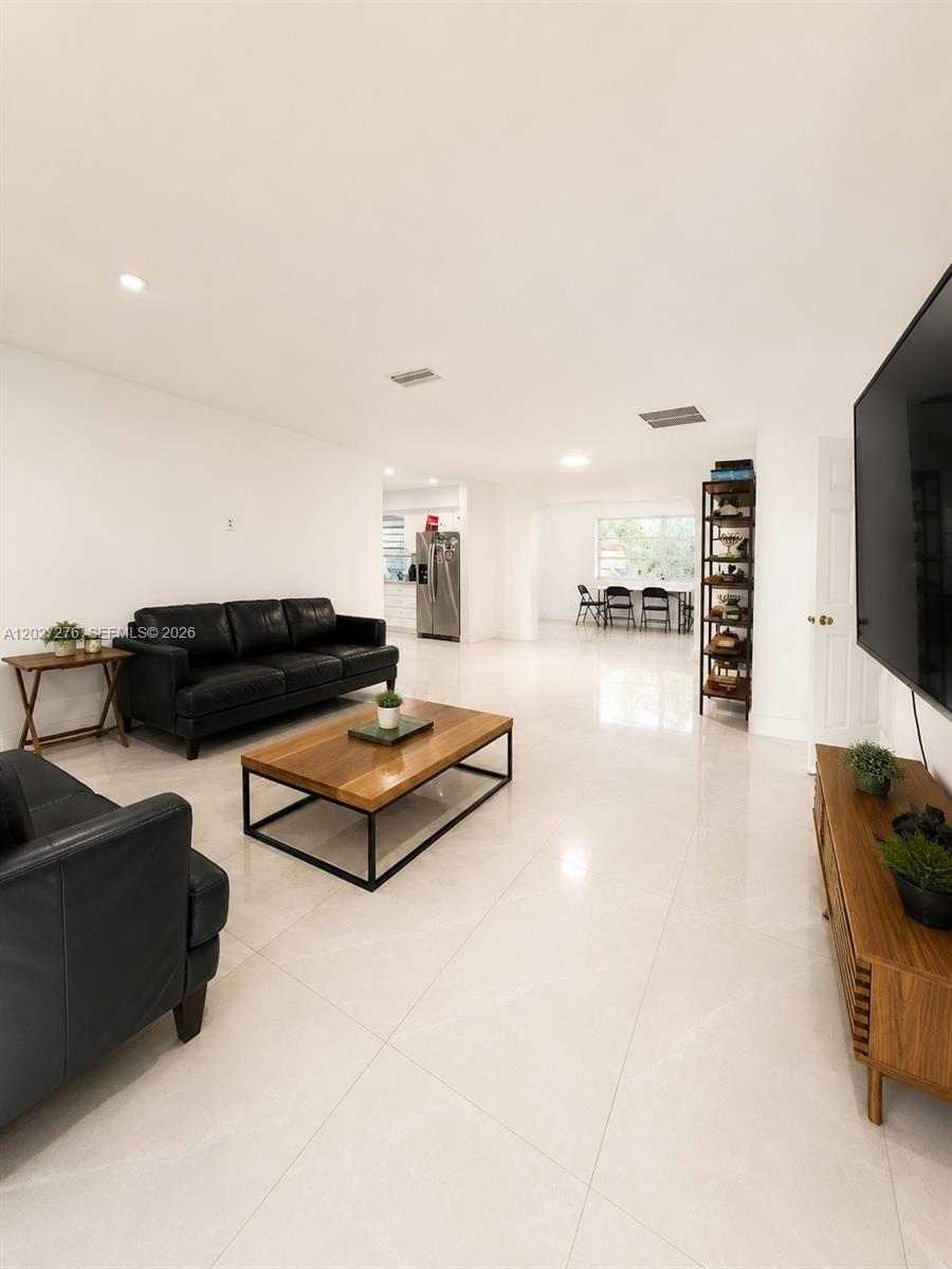 A living room features white tile floors, black leather sofas, and a wooden coffee table — 1109 NE 4th Ct, Hallandale Beach FL 33009, HALLANDALE BEACH, FL