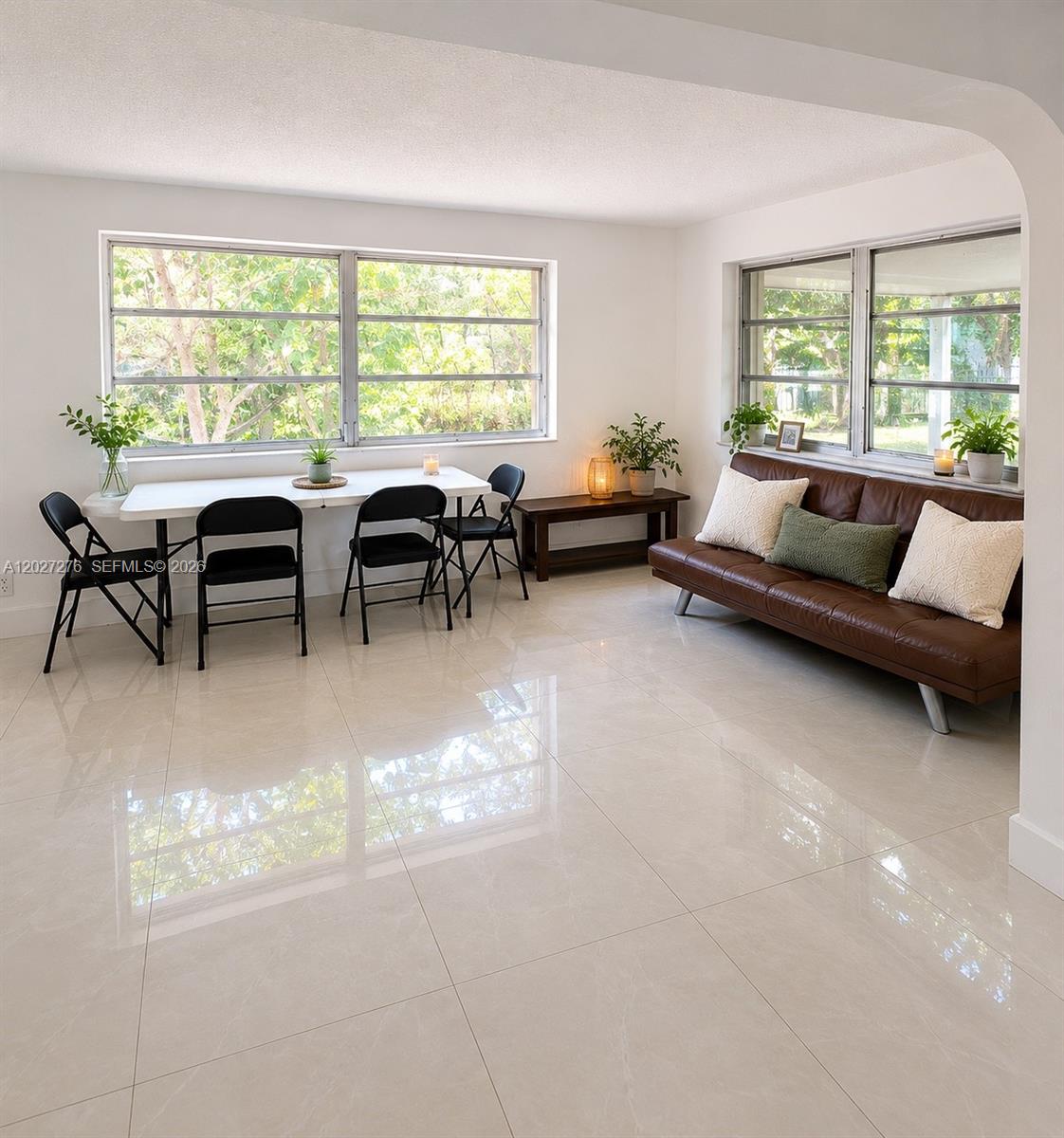 A bright living and dining area features white tile floors, large windows, and modern furniture — 1109 NE 4th Ct, Hallandale Beach FL 33009, HALLANDALE BEACH, FL