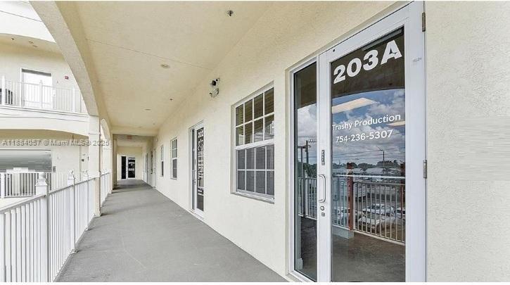 An exterior walkway leads past several commercial office doors with glass panels and white railings — 100 N State Road 7 # 203A, Margate FL 33063, MARGATE, FL
