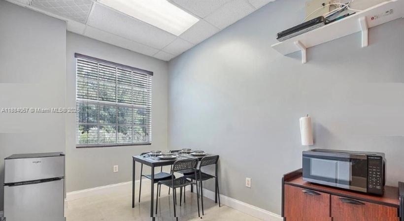 A small dining area features a table with four chairs, a microwave, and a refrigerator — 100 N State Road 7 # 203A, Margate FL 33063, MARGATE, FL