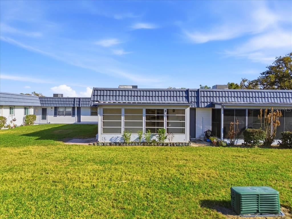 A view of the rear exterior of a single-story home with a screened-in porch — 205 ANDOVER PLACE N UNIT 119, SUN CITY CENTER, FL