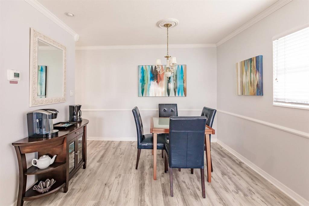 A dining room features a wooden table with four blue chairs and a side cabinet — 6020 MIDNIGHT PASS ROAD UNIT 4, SARASOTA, FL