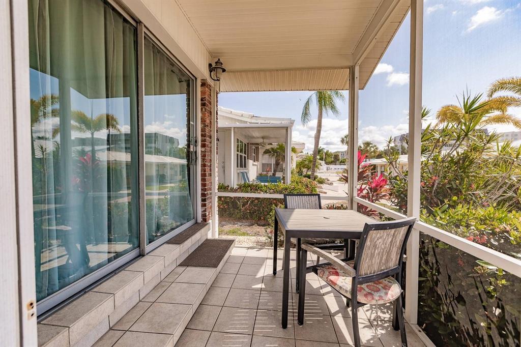 A screened-in patio with tile flooring, a small dining set, and sliding glass doors — 6020 MIDNIGHT PASS ROAD UNIT 4, SARASOTA, FL