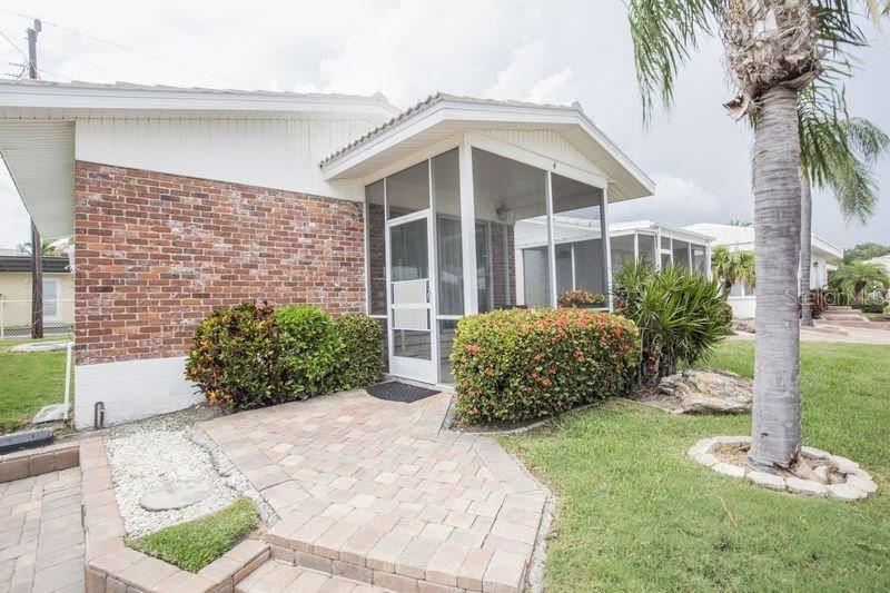 A brick-sided home features a screened-in porch, a paver walkway, and a palm tree — 6020 MIDNIGHT PASS ROAD UNIT 4, SARASOTA, FL