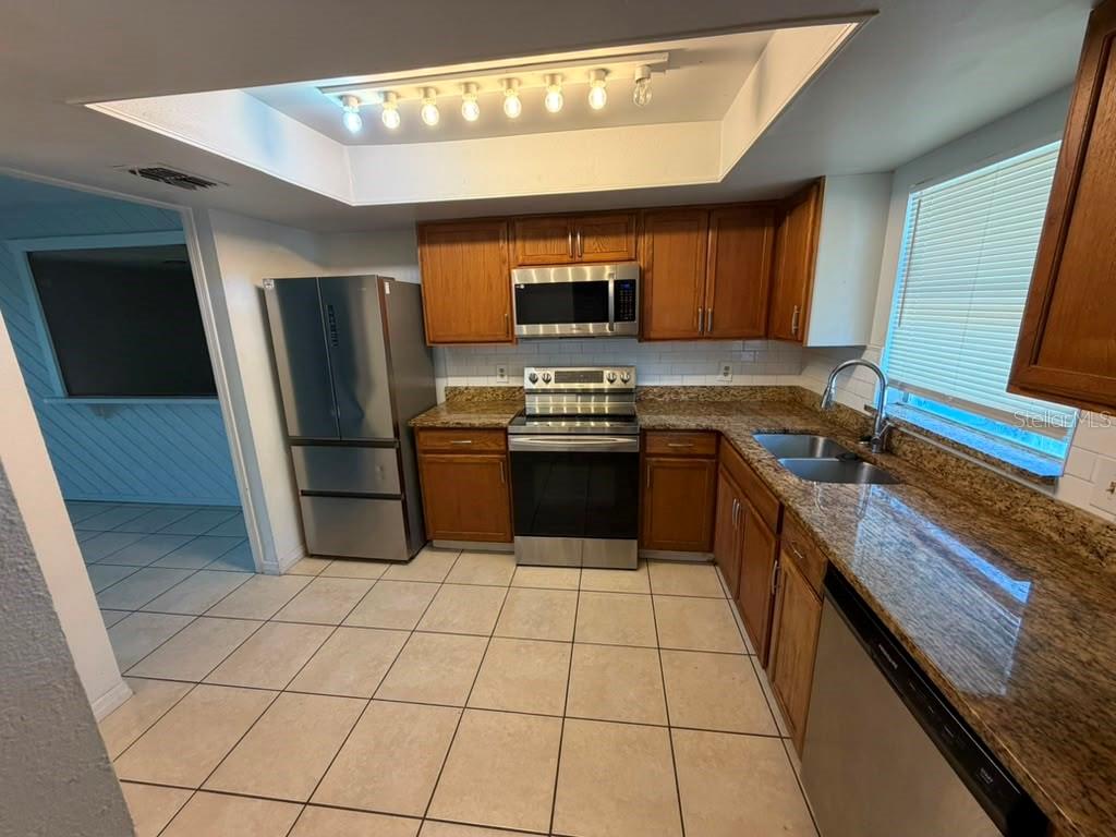 A kitchen with wood cabinets, granite countertops, stainless steel appliances, and a tray ceiling — 2434 RIO PINAR LAKES BOULEVARD, ORLANDO, FL