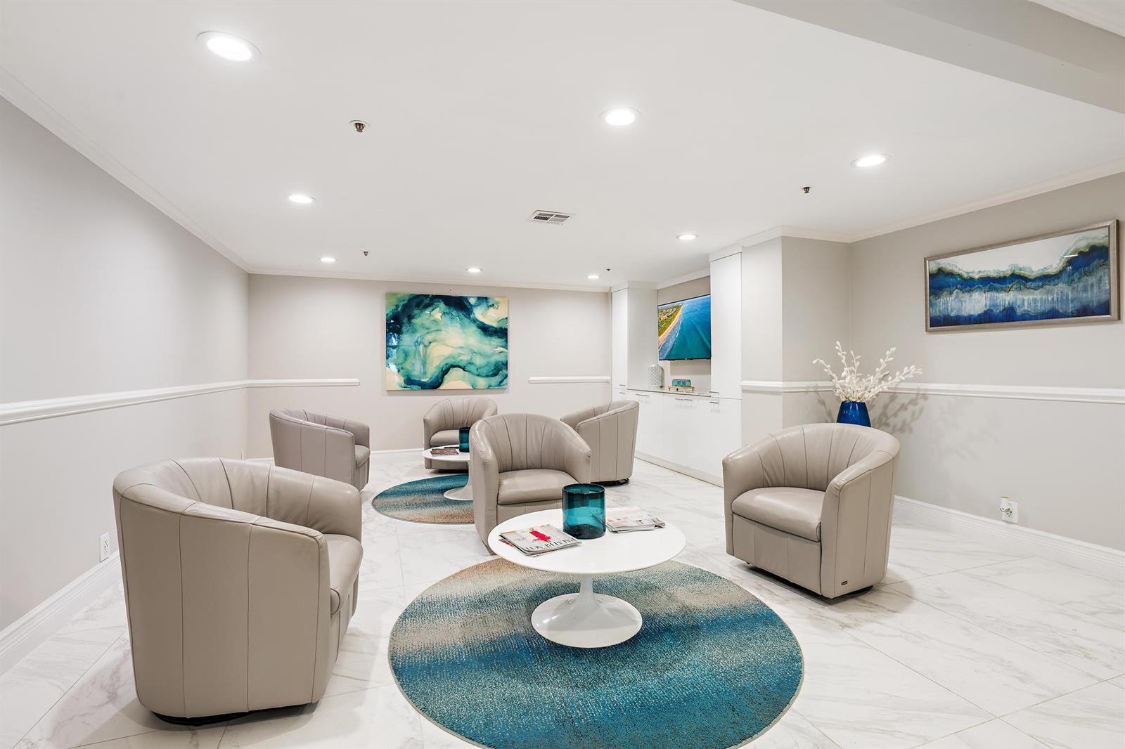 A modern lounge area features light gray leather armchairs, circular blue rugs, and white tables — 5280 N Ocean Drive # 8b, Riviera Beach FL 33404, RIVIERA BEACH, FL