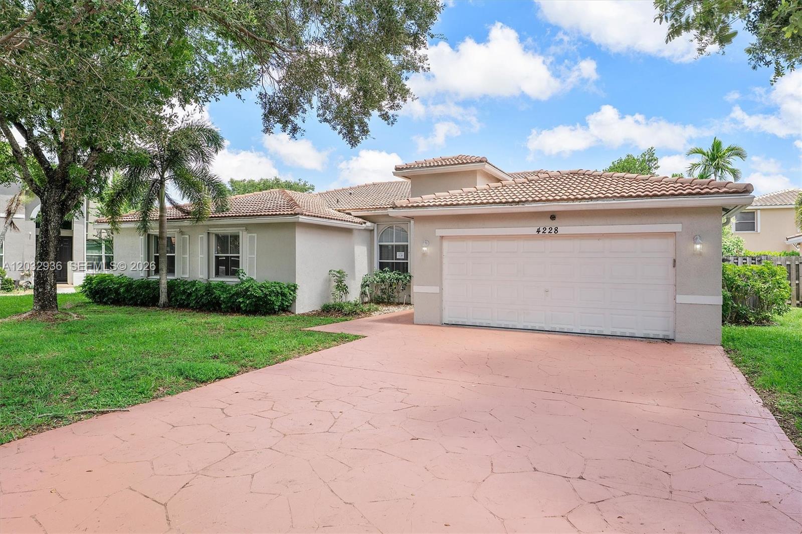 A single-story house with a tiled roof, beige stucco walls, and a patterned concrete driveway — 4228 NW 41st Ln, Coconut Creek FL 33073, COCONUT CREEK, FL
