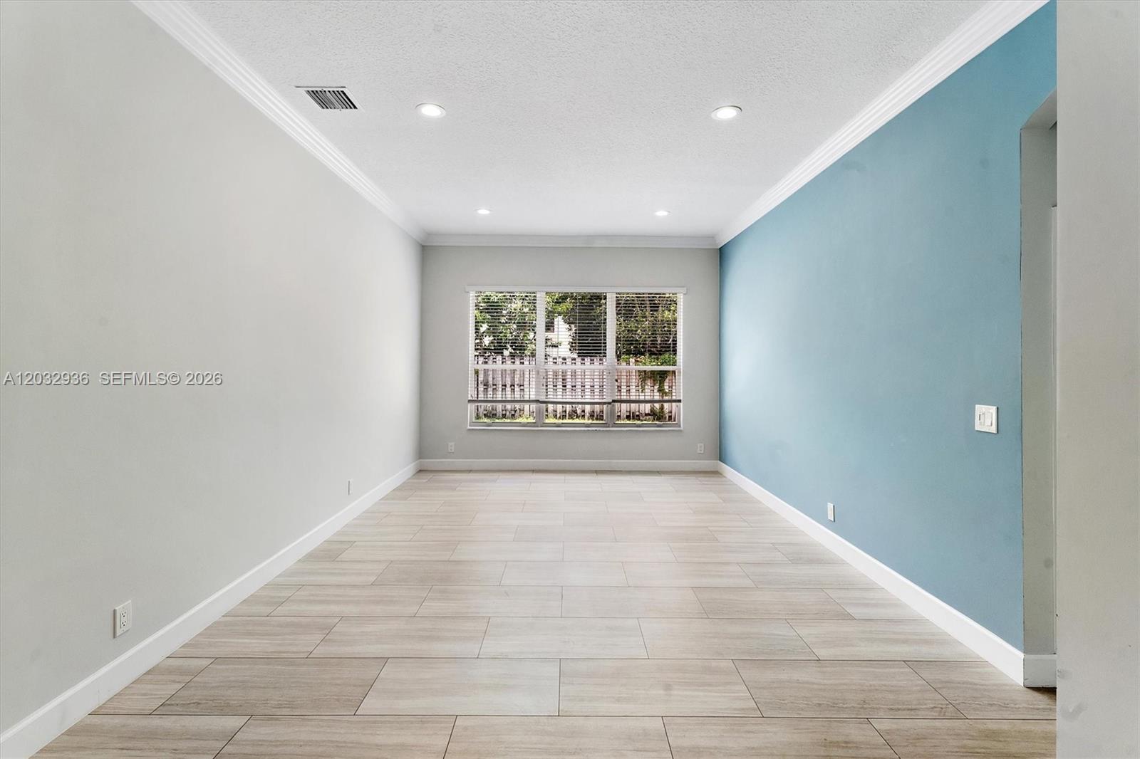 This room features light-colored tile flooring, a blue accent wall, and a large window — 4228 NW 41st Ln, Coconut Creek FL 33073, COCONUT CREEK, FL