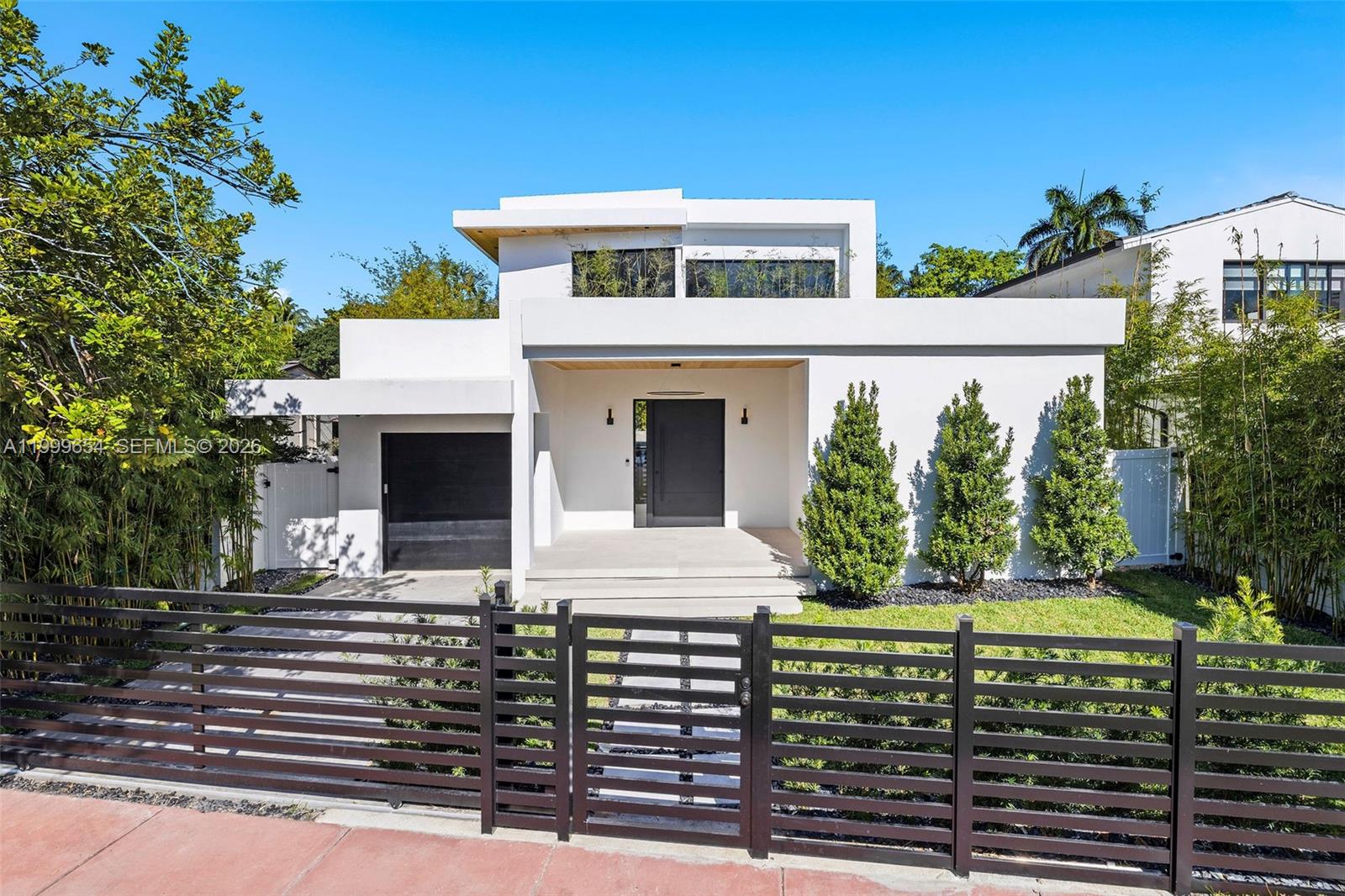 A modern white two-story house features a black garage door, front door, and metal fence — 325 W 63rd St, Miami Beach FL 33141, MIAMI BEACH, FL