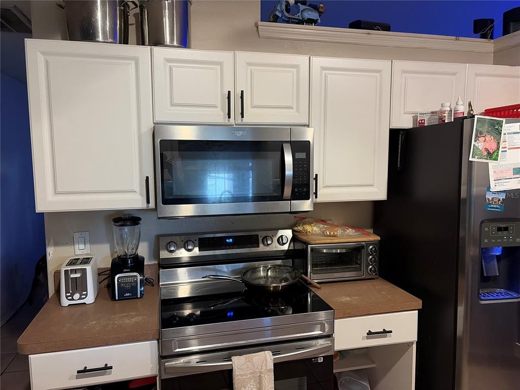 A kitchen features white cabinets, stainless steel appliances, and a brown countertop — 1104 67TH AVENUE W, BRADENTON, FL
