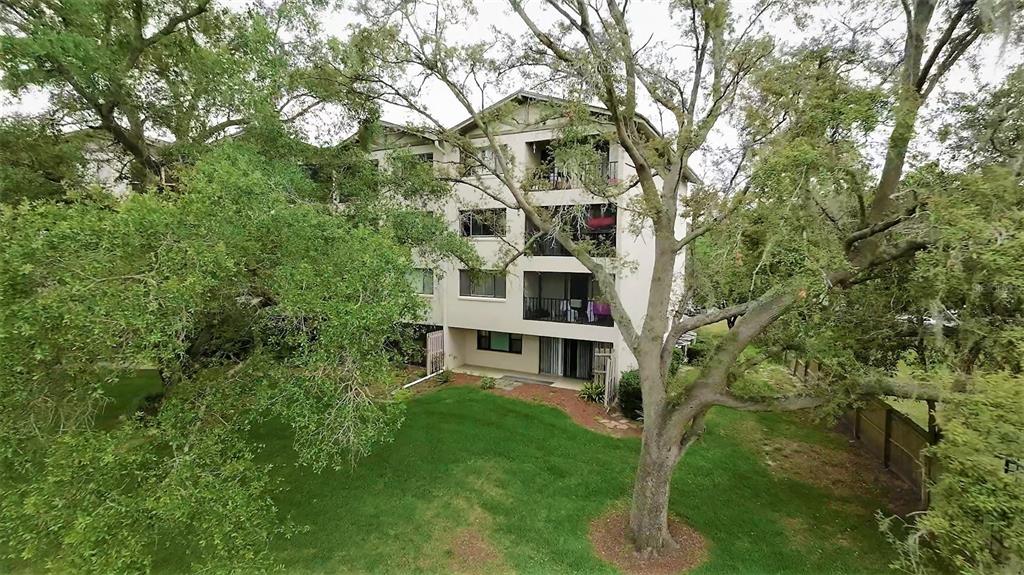 A kitchen island with bar stools overlooks a dining area and a balcony with trees — 1036 BONAIRE DRIVE UNIT 2836, ALTAMONTE SPRINGS, FL