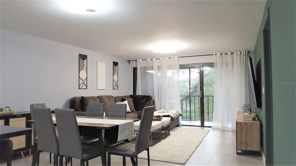 A dining area and living room with a brown sofa, dining table, and sliding glass doors — 1036 BONAIRE DRIVE UNIT 2836, ALTAMONTE SPRINGS, FL
