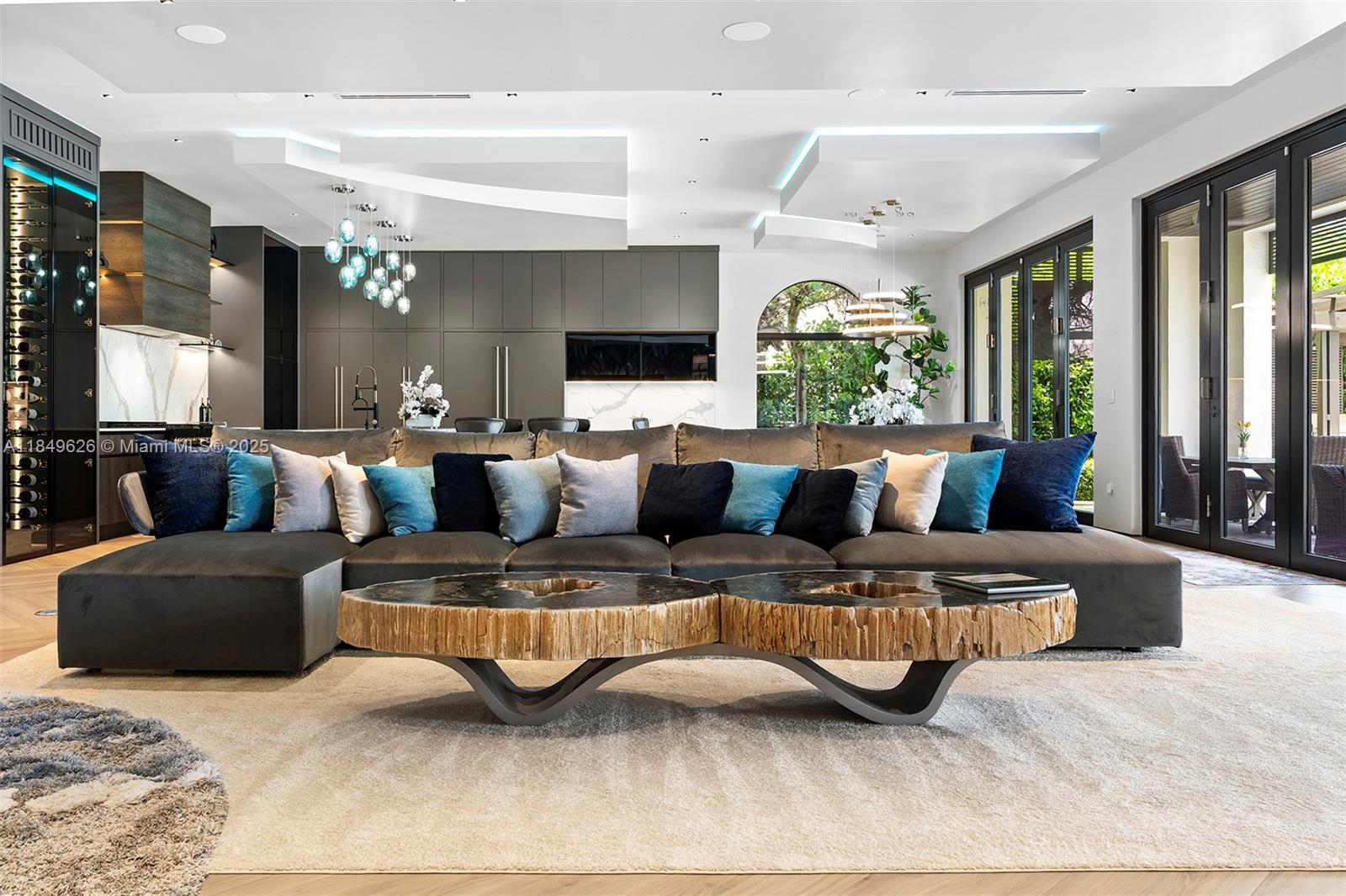A modern living room features a large sectional sofa, two live-edge coffee tables, and an open kitchen — FORT LAUDERDALE, FL