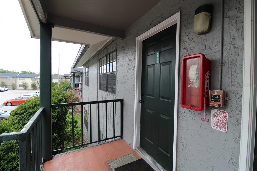 An exterior view of an apartment entrance with a dark door and a fire alarm — 201 POINSETTIA PINE COURT UNIT 202, TAMPA, FL