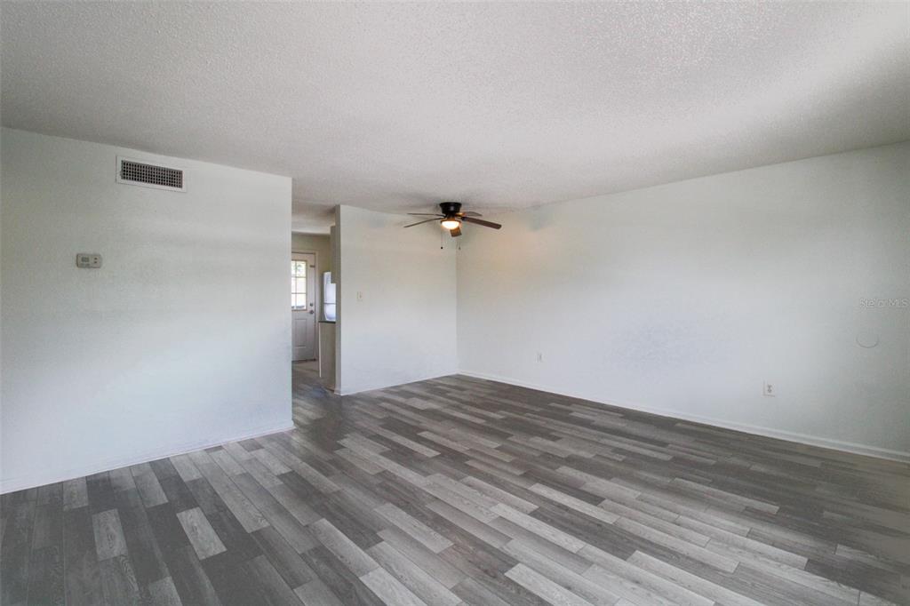 An empty room with gray wood-look flooring, white walls, and a ceiling fan — 201 POINSETTIA PINE COURT UNIT 202, TAMPA, FL