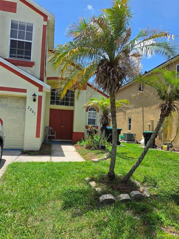 A two-story house with a red front door, a palm tree, and a grassy front yard — 2261 BLUE SAPPHIRE CIRCLE, ORLANDO, FL