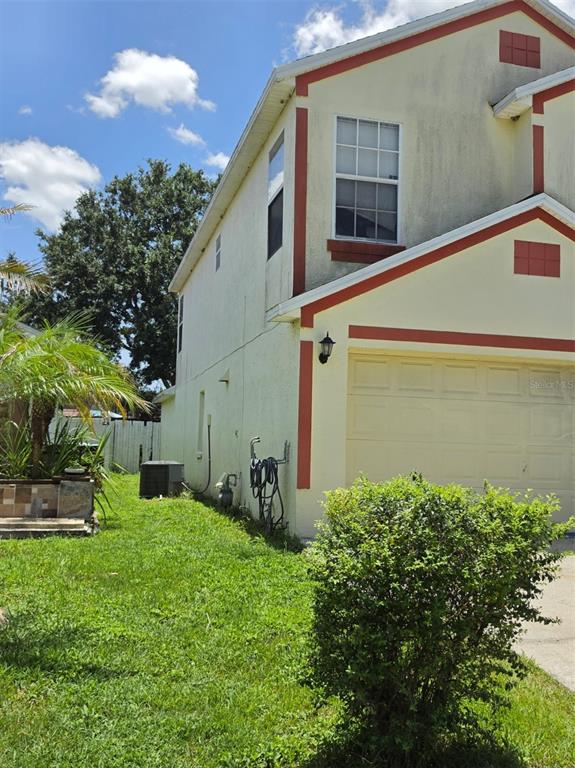 A two-story house exterior with a garage, side yard, and visible air conditioning unit — 2261 BLUE SAPPHIRE CIRCLE, ORLANDO, FL
