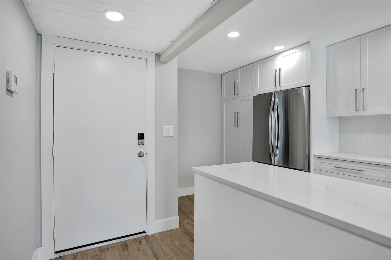 A white kitchen features a stainless steel refrigerator, white cabinetry, and a quartz countertop — 7 Royal Palm Way # 404, Boca Raton FL 33432, BOCA RATON, FL