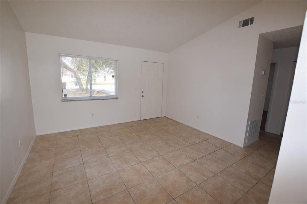 An empty room with white walls, beige tile flooring, a window, and a white door — 3264 SPLIT WILLOW DRIVE, ORLANDO, FL