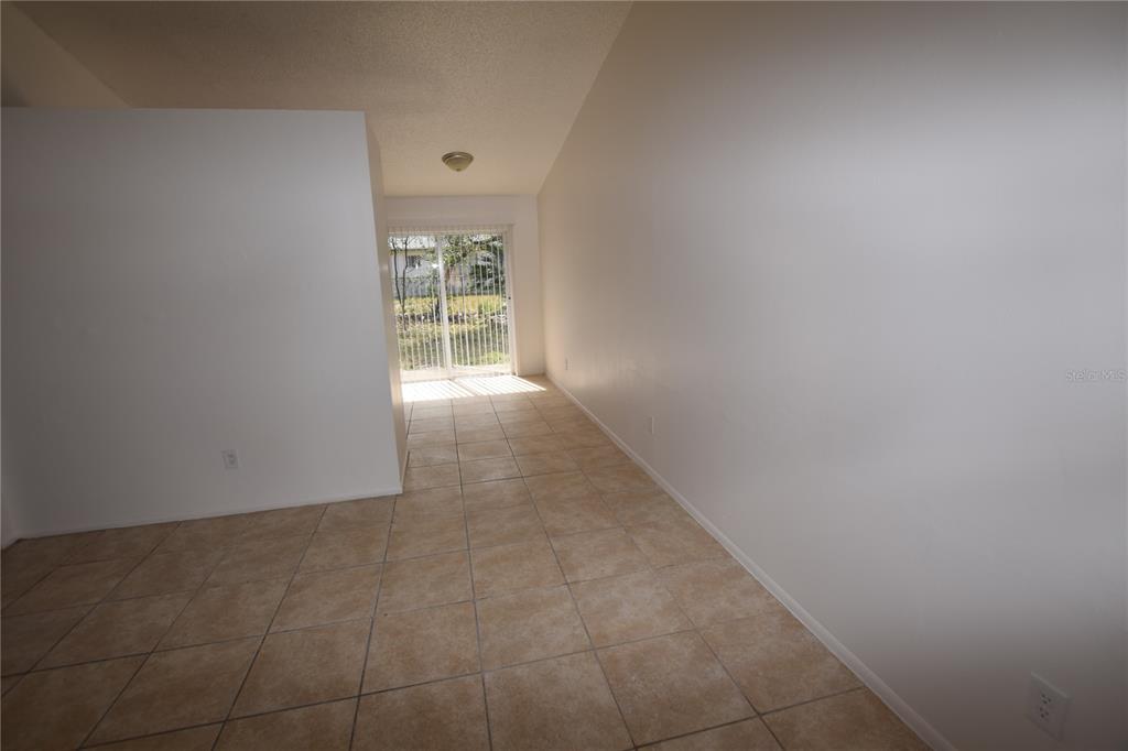 An empty room with beige tile flooring, white walls, and a sliding glass door — 3264 SPLIT WILLOW DRIVE, ORLANDO, FL