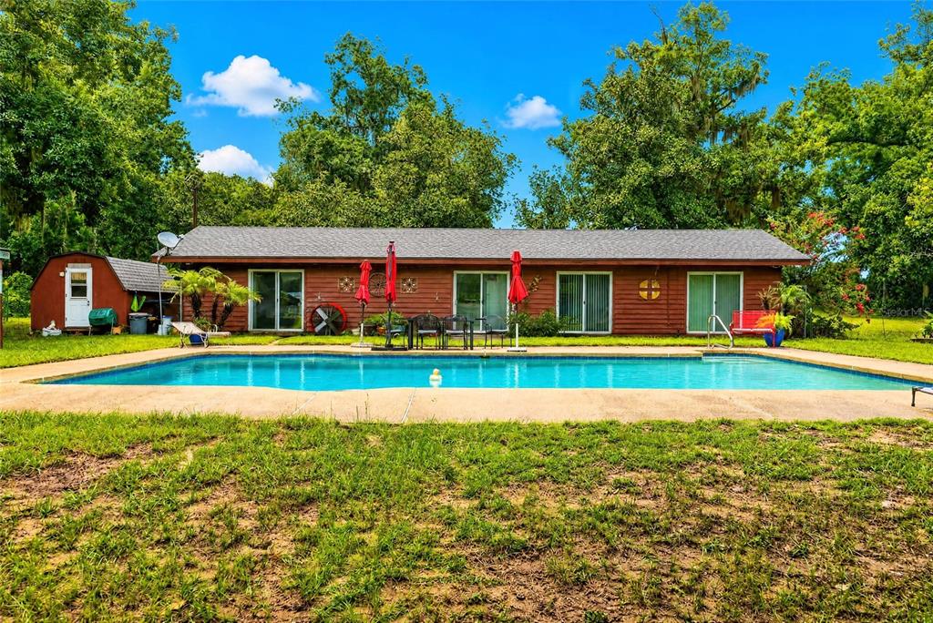A single-story red house with a swimming pool in the backyard — 35446 FOURAKER DRIVE, FRUITLAND PARK, FL