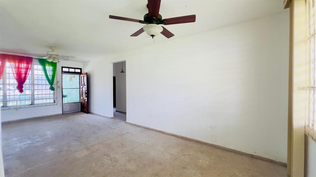 An empty living room features white walls, tile flooring, and two ceiling fans — #9 CALLE REPARTO GONZALEZ, AGUADA, PR