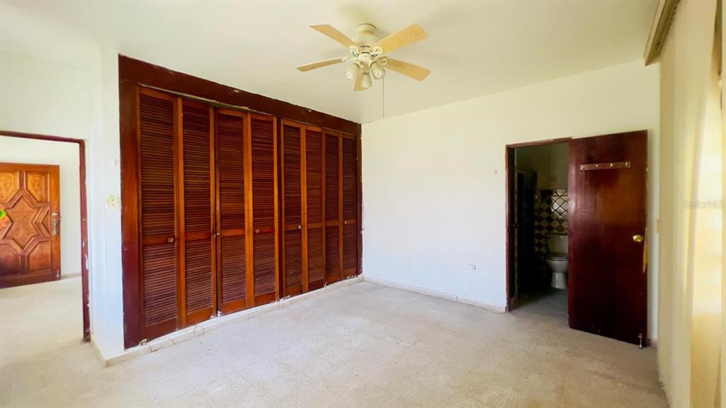 A bedroom features a large wooden louvered closet, a ceiling fan, and an attached bathroom — #9 CALLE REPARTO GONZALEZ, AGUADA, PR